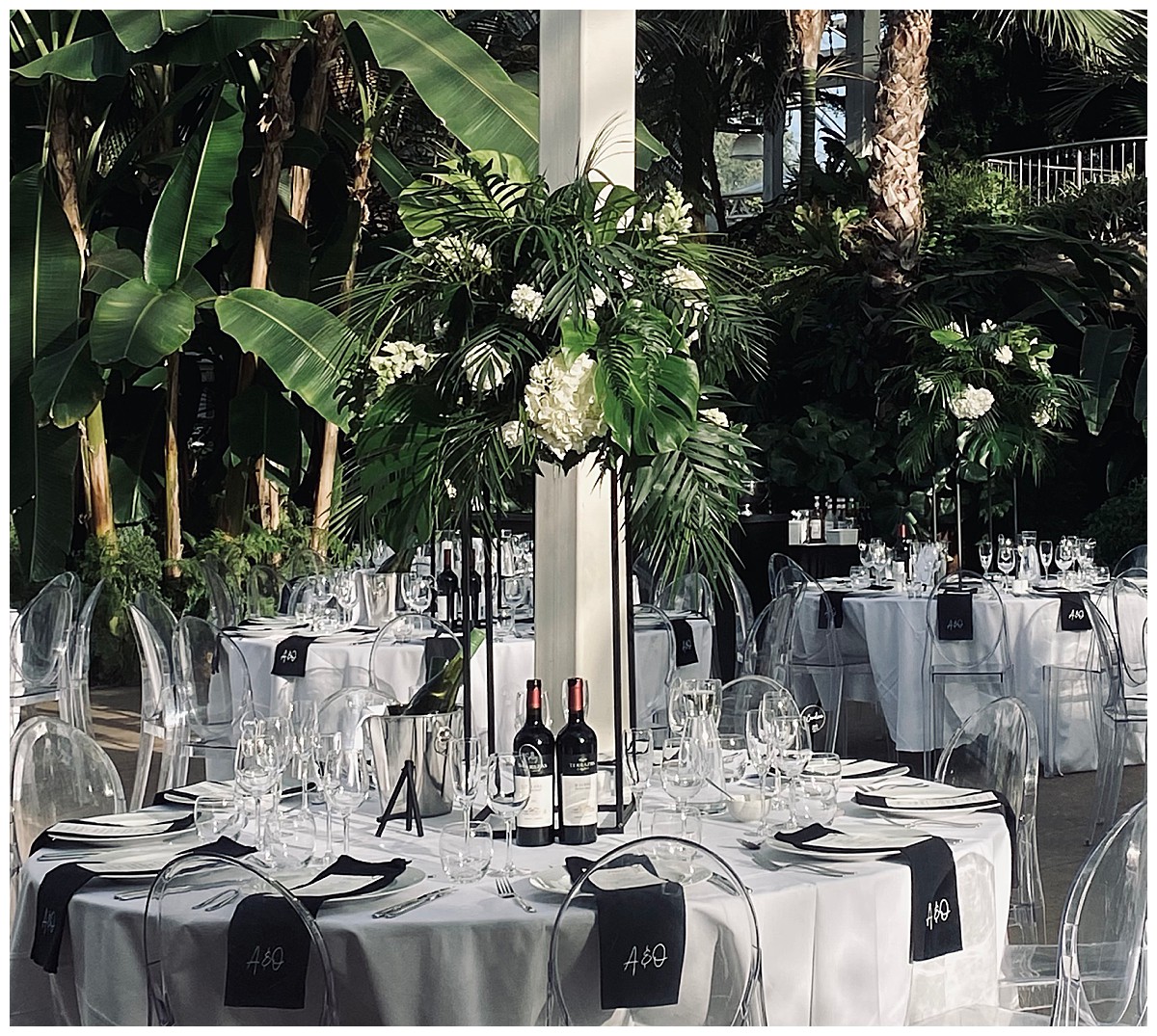 botanical tropical garden inspired black & white wedding centrepiece with black tall geometric stands and white flowers and lots of foliage